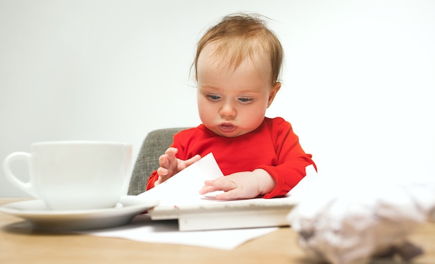 Combien de documents puis-je signer enfant bébé fille assise avec le clavier d'un ordinateur moderne ou d'un ordinateur portable en studio blanc.