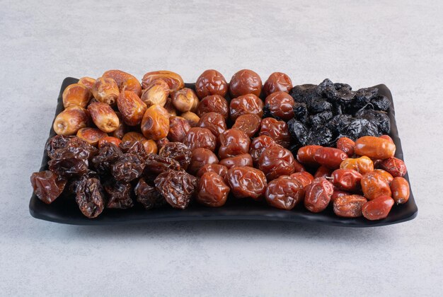 Combinaison de fruits secs sur un plateau sur une surface en béton.