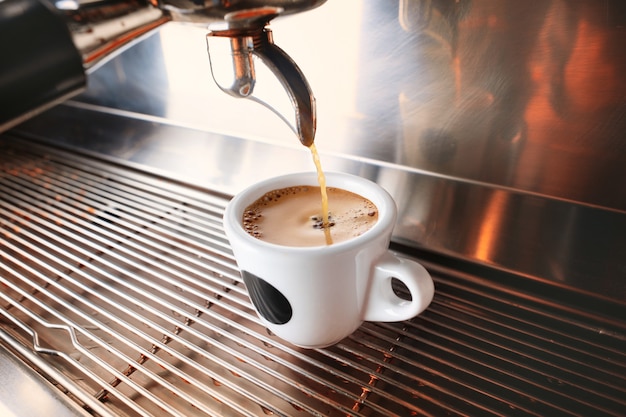 Commencez votre journée avec une tasse de boisson aromatique. Café expresso noir élégant faisant la machine à café, tourné dans le café.