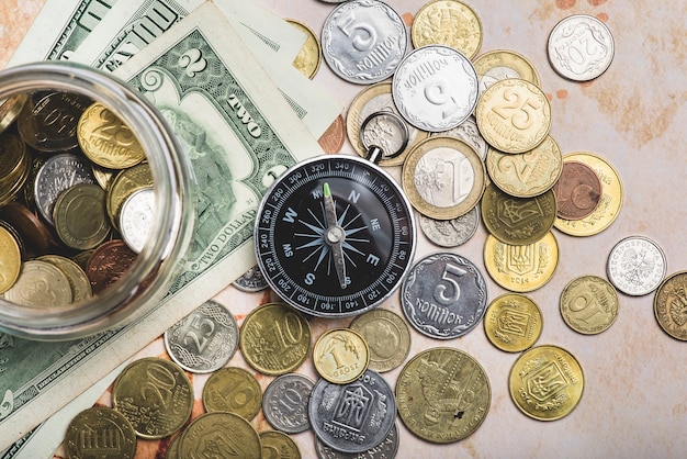 Photo gratuite compass avec des pièces de monnaie et billets de banque