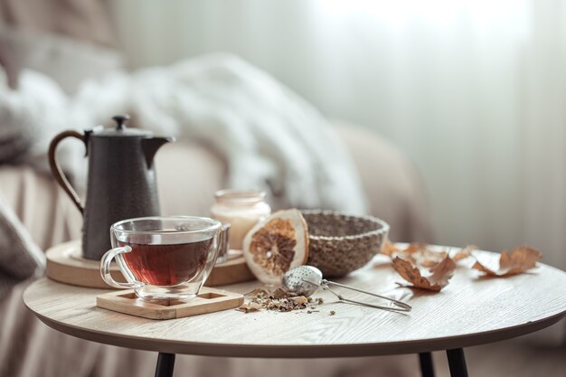 Composition d'automne avec une tasse de thé, une théière et des détails de décoration d'automne sur un arrière-plan flou.