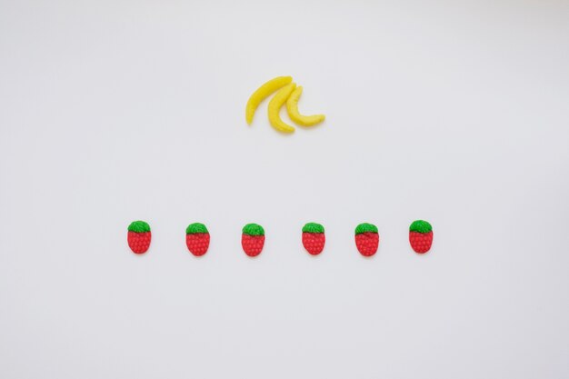 Composition avec des bananes aux bonbons et des fraises