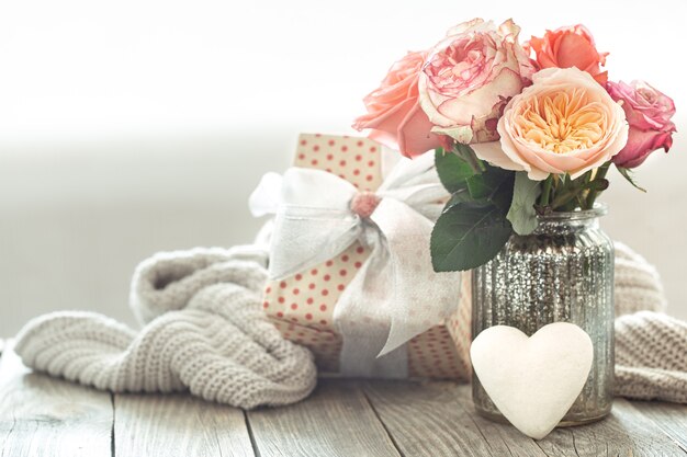 Composition avec un bouquet de roses dans un vase en verre avec un coffret cadeau