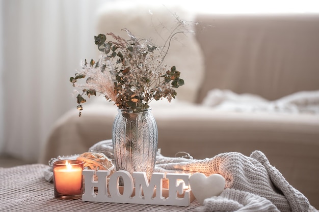 Composition confortable avec des bougies décoratives pour la maison et un vase avec des fleurs séchées