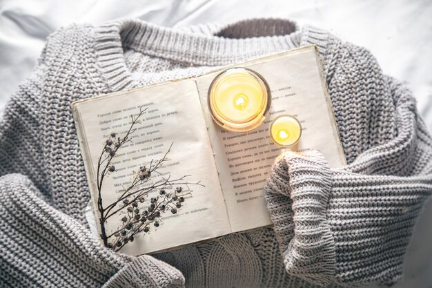 Photo gratuite composition confortable avec un livre, un élément tricoté et des bougies vue de dessus