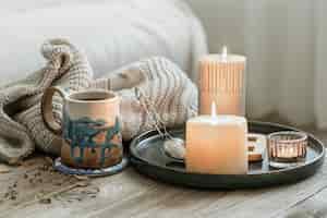 Photo gratuite composition confortable avec une tasse en céramique, des bougies et un élément tricoté