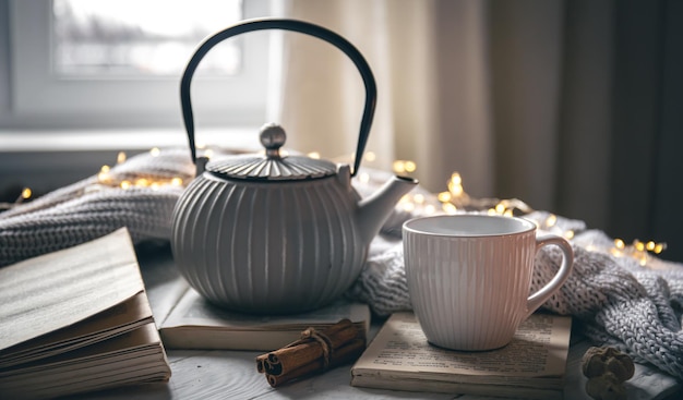 Photo gratuite composition confortable avec une théière une tasse et un livre sur un arrière-plan flou