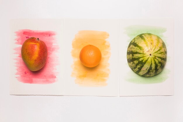 Photo gratuite composition de délicieux fruits entiers mélangés sur une surface aquarelle multicolore