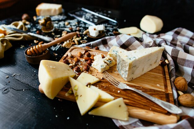 Composition de différentes variétés de fromage avec du miel, des noix, des olives