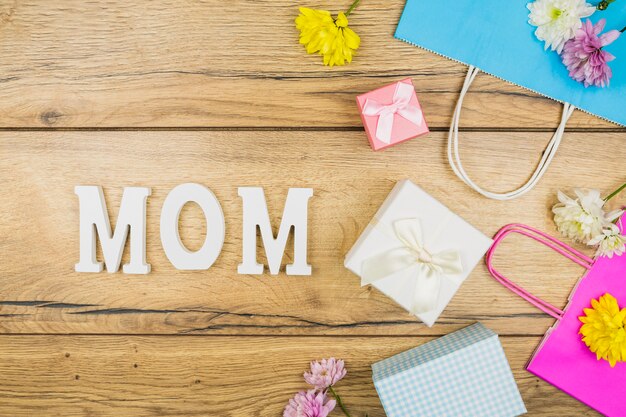 Composition du titre de maman près des fleurs fraîches, des boîtes à cadeaux et des paquets de papier