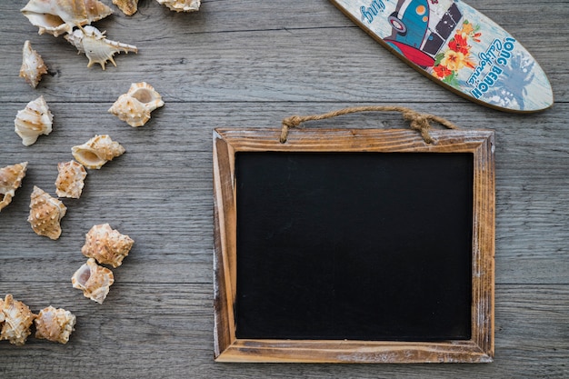 Photo gratuite composition d'été avec ardoise blanche, planche de surf et coquillage