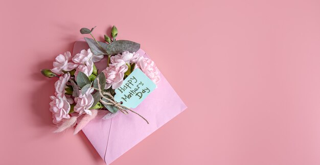 Composition festive avec une enveloppe avec des fleurs fraîches et l'inscription à plat Happy Mother's Day.