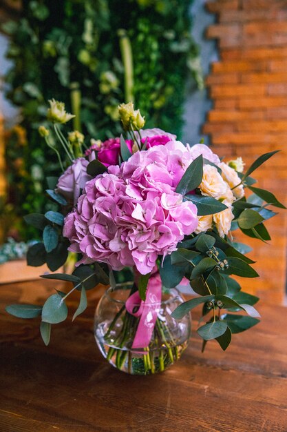 Composition de fleurs dans un vase en verre hortensias roses orange vif vue latérale