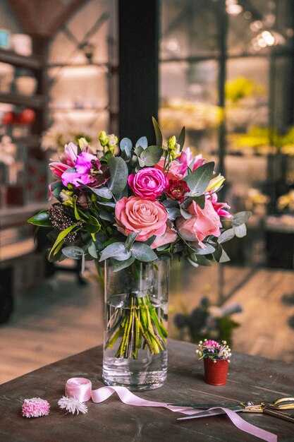 Composition de fleurs mélange roses chrysanthèmes ruban ciseaux vue latérale