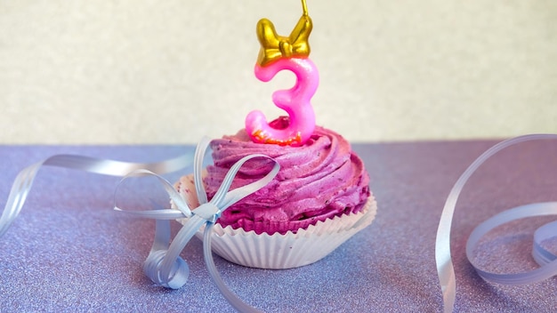 Composition de gâteau rose avec des bandes numéro trois et un fond argenté brillant