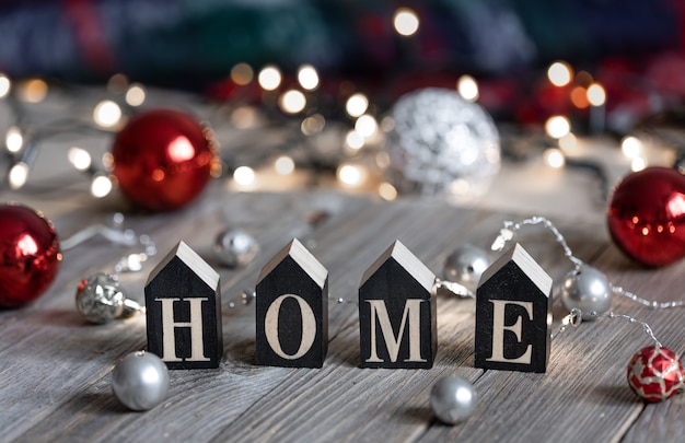 Photo gratuite composition d'hiver avec le mot décoratif home et boules de noël sur fond flou avec bokeh.