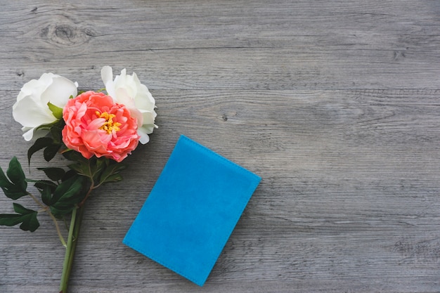 Photo gratuite composition avec livre bleu et fleurs