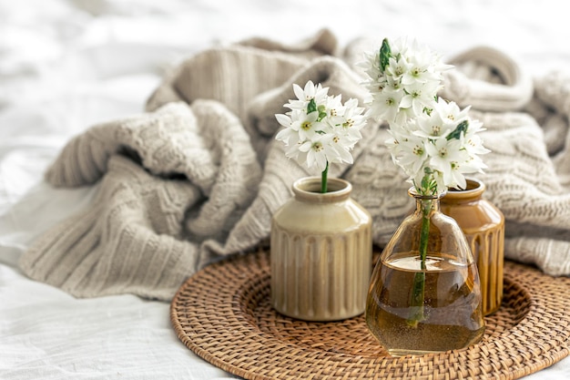 Composition maison avec des fleurs dans des vases et un élément tricoté