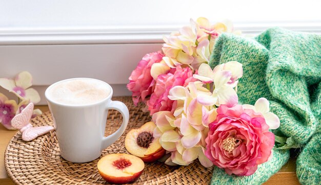 Composition maison avec une tasse de fleurs de café et un élément tricoté