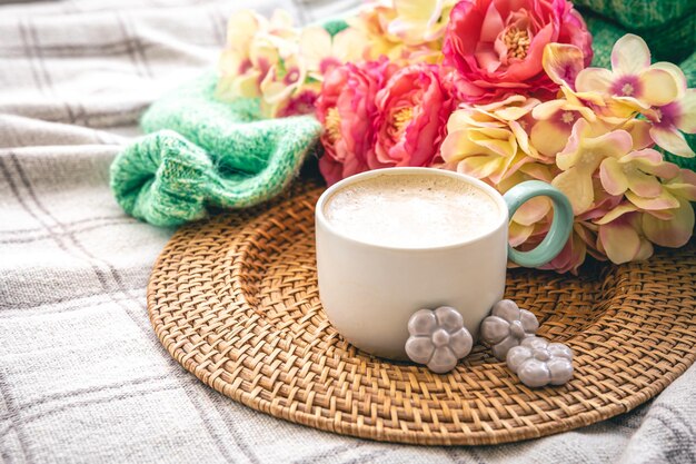 Composition maison avec une tasse de fleurs de café et un élément tricoté