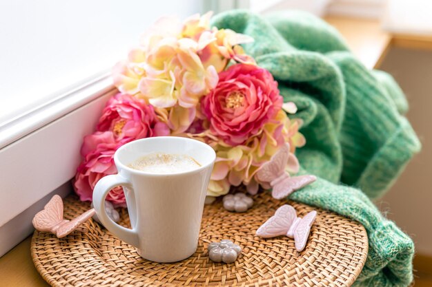 Composition maison avec une tasse de fleurs de café et un élément tricoté