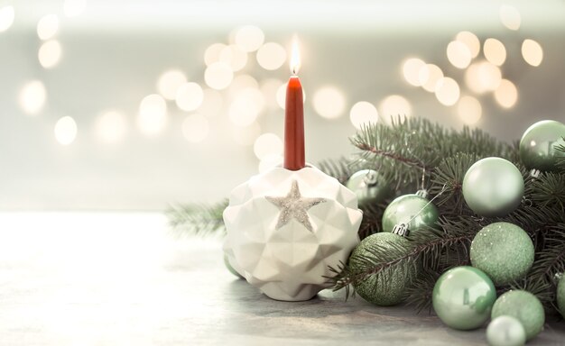 Composition de Noël avec une bougie dans un chandelier et des boules de Noël