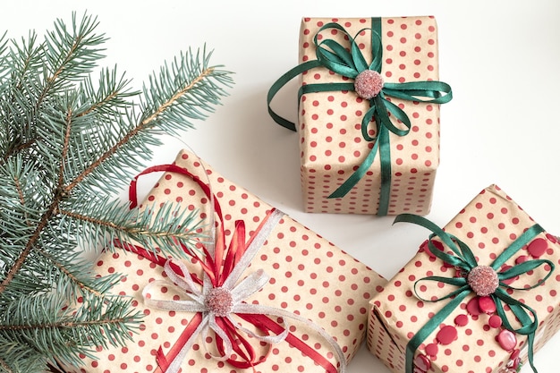 Composition de Noël de divers coffrets cadeaux emballés dans du papier kraft et décorés de rubans de satin. Vue de dessus, mise à plat. Mur blanc.