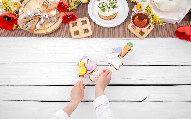 Composition de Pâques avec du pain d'épice brillant sur des bâtons en mains féminines. Le concept de cuisine pour les vacances de Pâques.