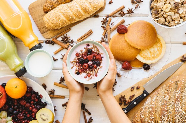 Composition de petit-déjeuner avec les mains tenant un bol de yaourt