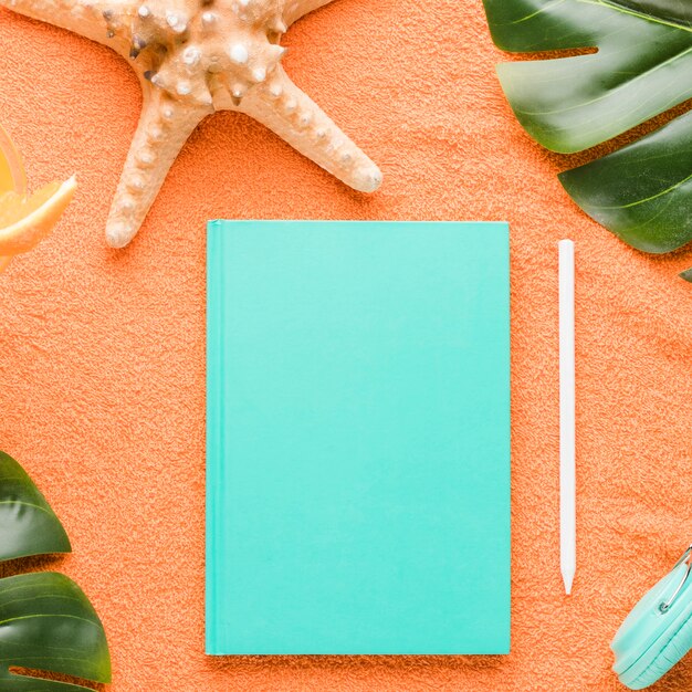 Composition de plage avec un cahier sur fond coloré