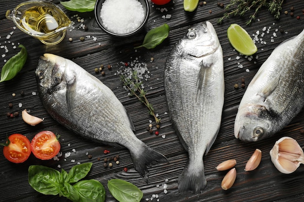 Composition à plat avec du poisson dorada cru sur une table en bois noire