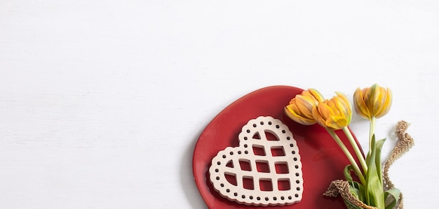 Composition pour la Saint-Valentin avec assiette, fleurs et vue de dessus de l'élément de décoration.