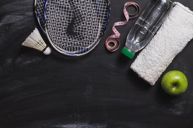 Composition avec la raquette de badminton, une bouteille d&#39;eau et de pomme