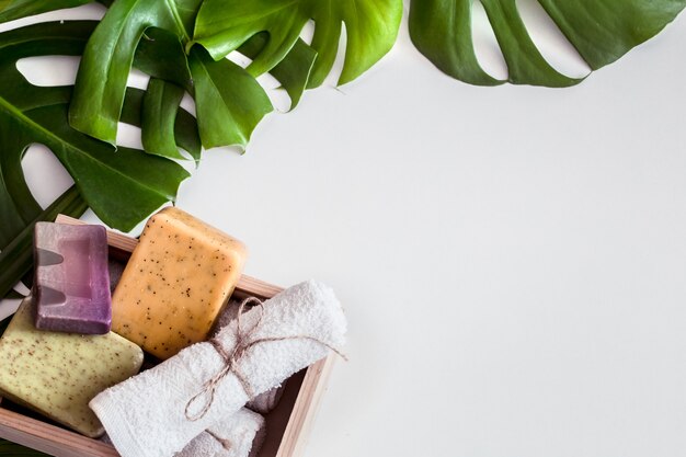 Composition de spa avec des feuilles tropicales sur fond blanc. Différents savons biologiques, concept de soins et de beauté, vue de dessus
