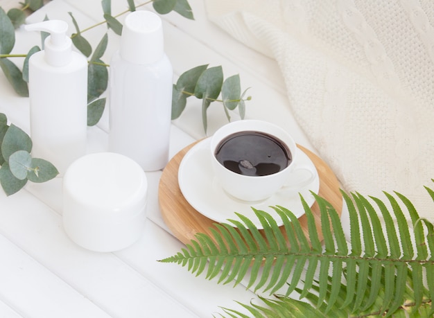 Composition de spa de pot de crème et bouteille de shampoing avec une tasse de café noir.