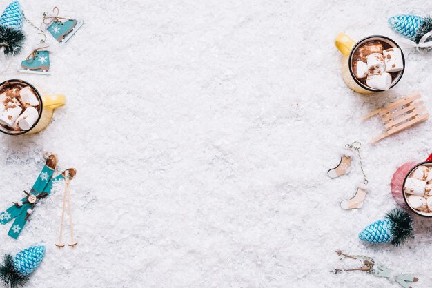 Composition de tasses près de jouets de Noël entre neige