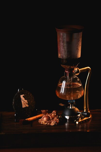 Composition de thé Thé Puer dans le siphon avec statue de Bouddha sur fond noir