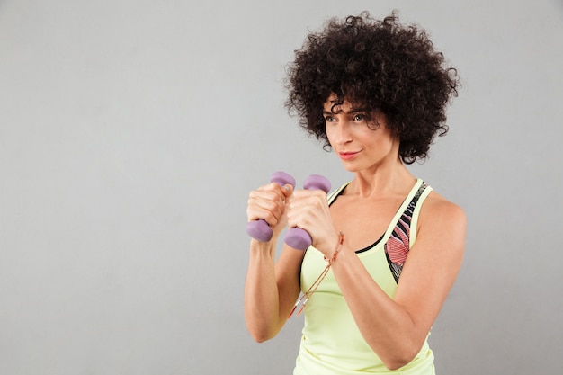 Photo gratuite concentré femme fitness bouclés faire de l'exercice avec des haltères