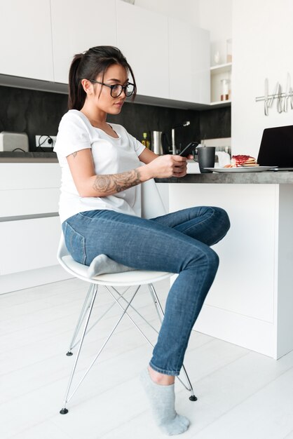 Concentré de jeune femme assise à la cuisine