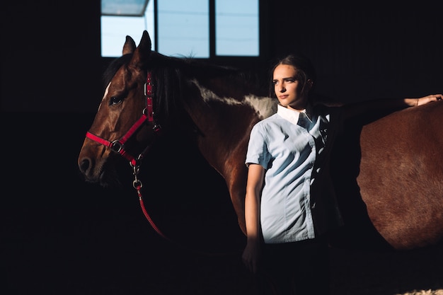 Concentré de jeune femme debout à l'extérieur près de son cheval