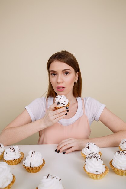 Concentré de jeune femme posant assis près de cupcakes