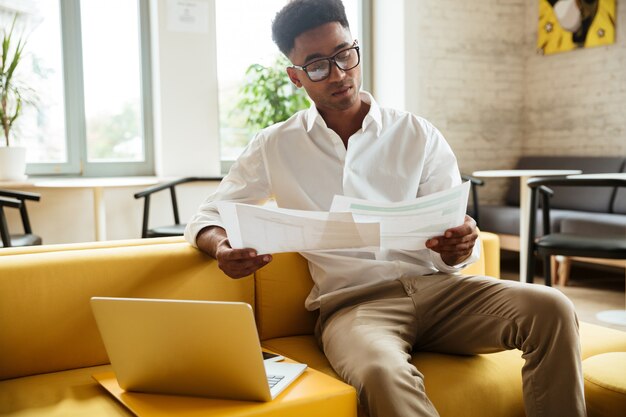 Concentré de jeune homme africain assis coworking