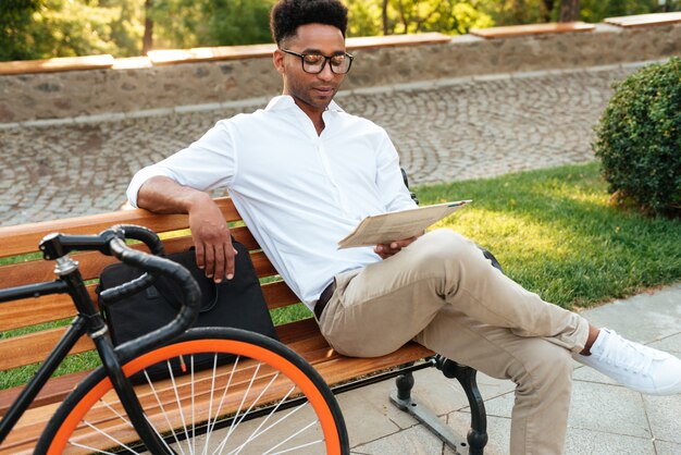 Concentré de jeune homme africain lisant le journal.