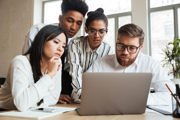 Concentré de jeunes collègues de travail sérieux à l'aide d'un ordinateur portable.