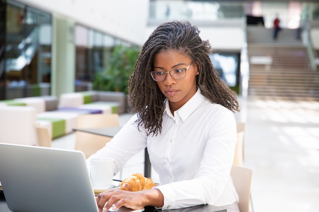 Concentré professionnel réussi prenant son petit déjeuner au café