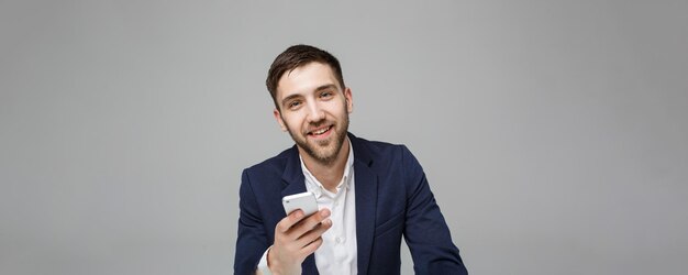 Concept d'affaires Portrait beau heureux bel homme d'affaires en costume jouant au téléphone portable et souriant avec un ordinateur portable au bureau de travail Fond blanc