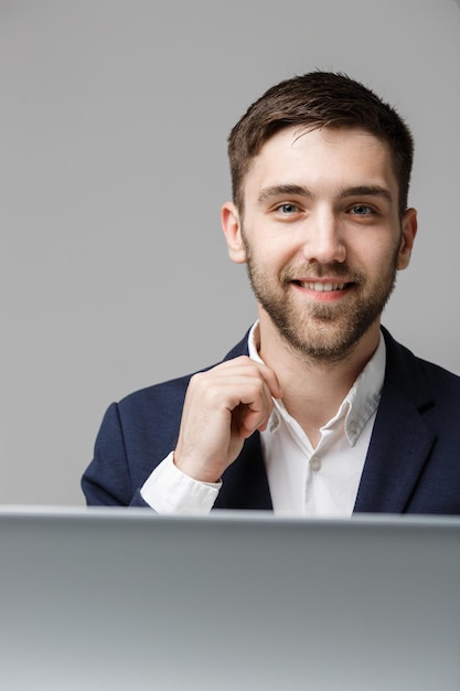 Concept d'affaires Portrait beau heureux bel homme d'affaires en costume souriant et implantation dans le bureau de travail Fond blanc