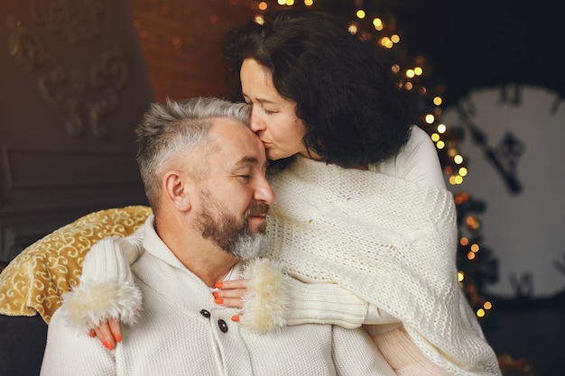 Concept d'âge et de personnes. Couple de personnes âgées avec boîte-cadeau sur fond de lumières. Femme dans un sweatre tricoté blanc.