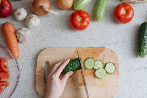 Concept d&#39;aliments sains avec une femme coupant le concombre