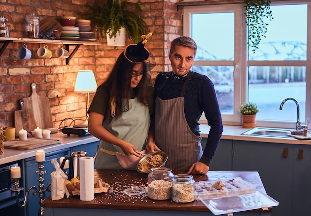 Concept d'amour et d'Halloween. Un couple attrayant avec du maquillage préparant ensemble le petit-déjeuner dans une cuisine de style loft le matin.